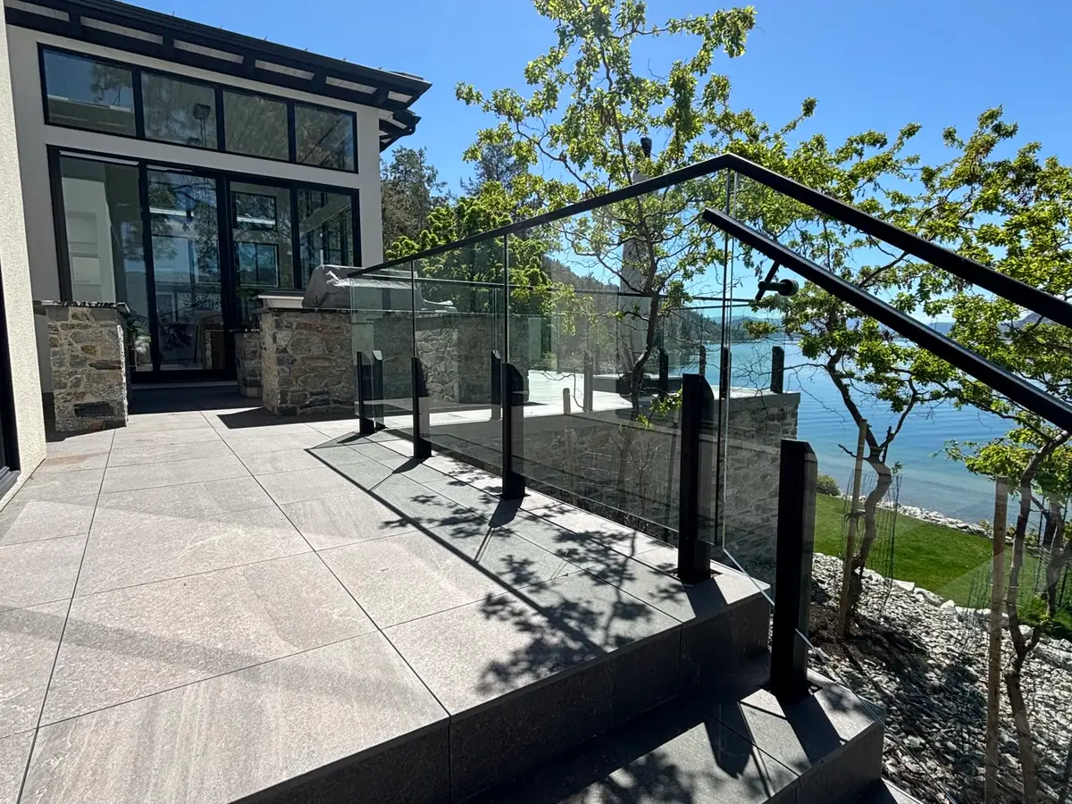 Clean lakeside stone patio, steps and glass railings from a Beam’s job