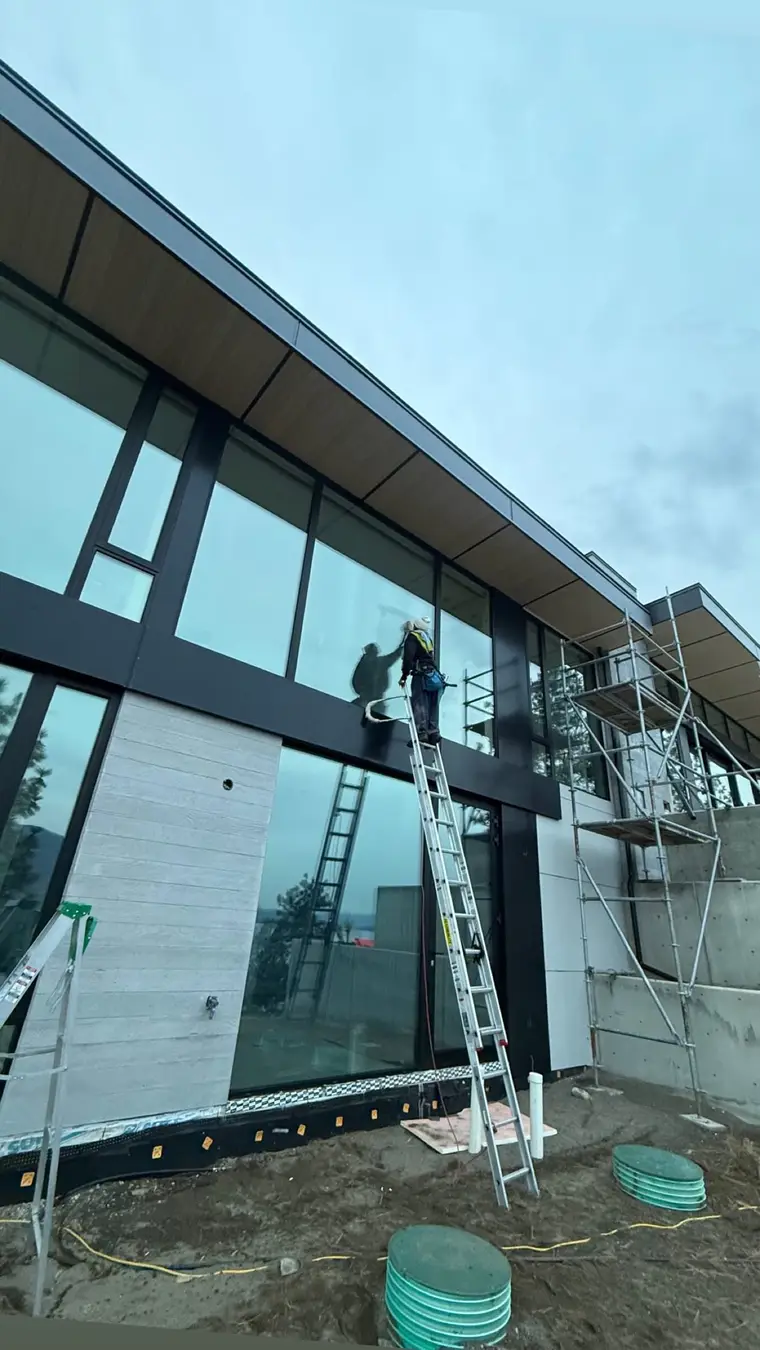 Beam's technician cleaning upper-level windows from a ladder