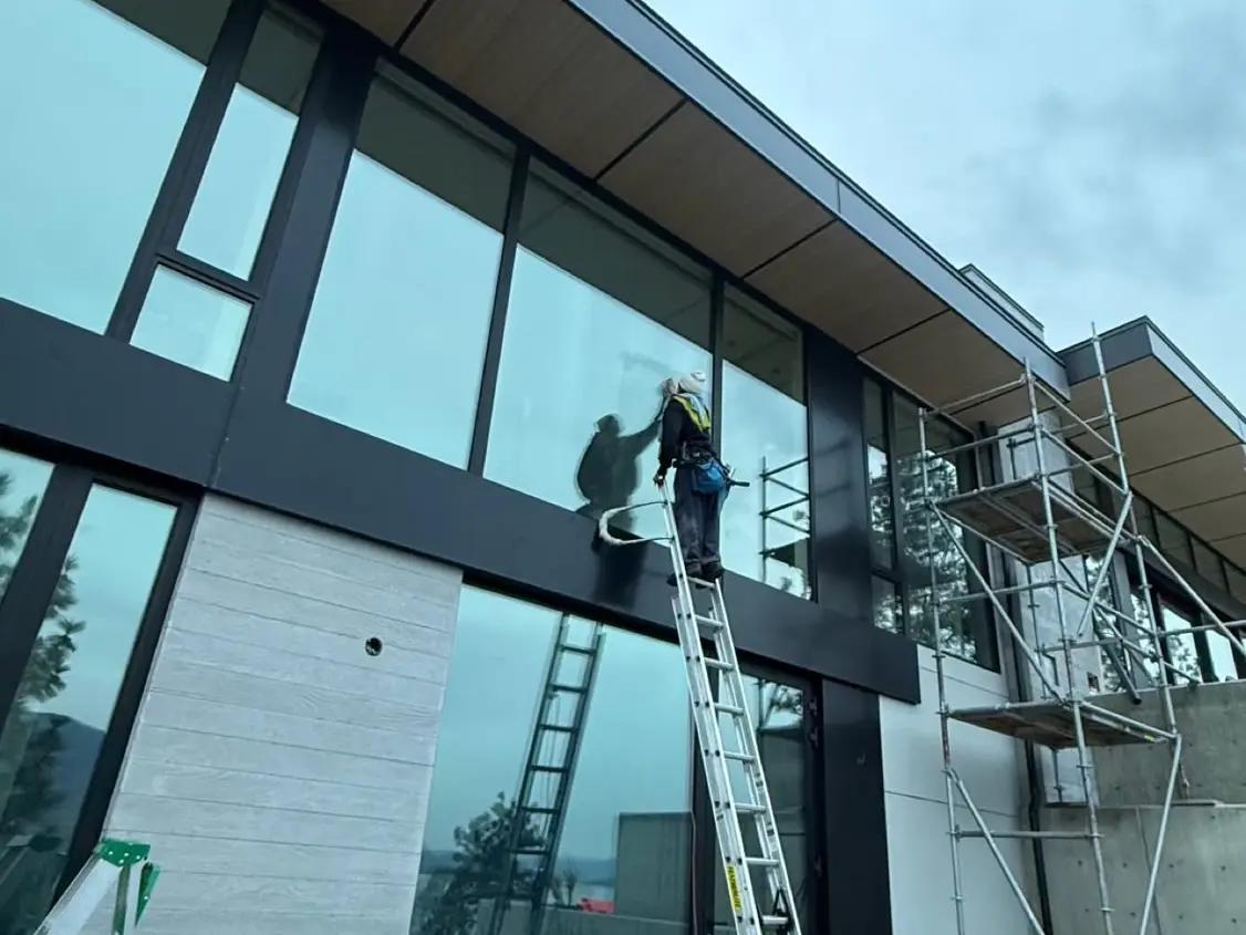 Beam's technician cleaning upper-level windows from a ladder